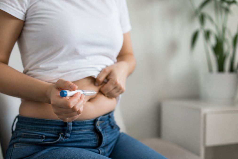 how-long-does-glp-1-take-to-work-timeline-results-1787107378 - Thrive Health Solutions - Thrive Health Solutions Person in a white shirt injects insulin pen into their abdomen.